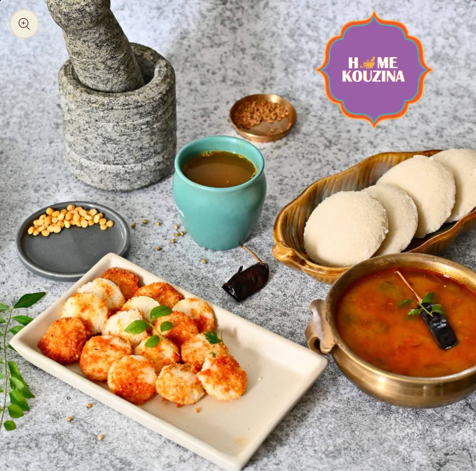 A platter of South Indian snacks featuring Madras Sambhar, Idlis, Rasam, and Idlis garnished with Milagai Podi or Molgai Podi/Gunpowder from Home Kouzina