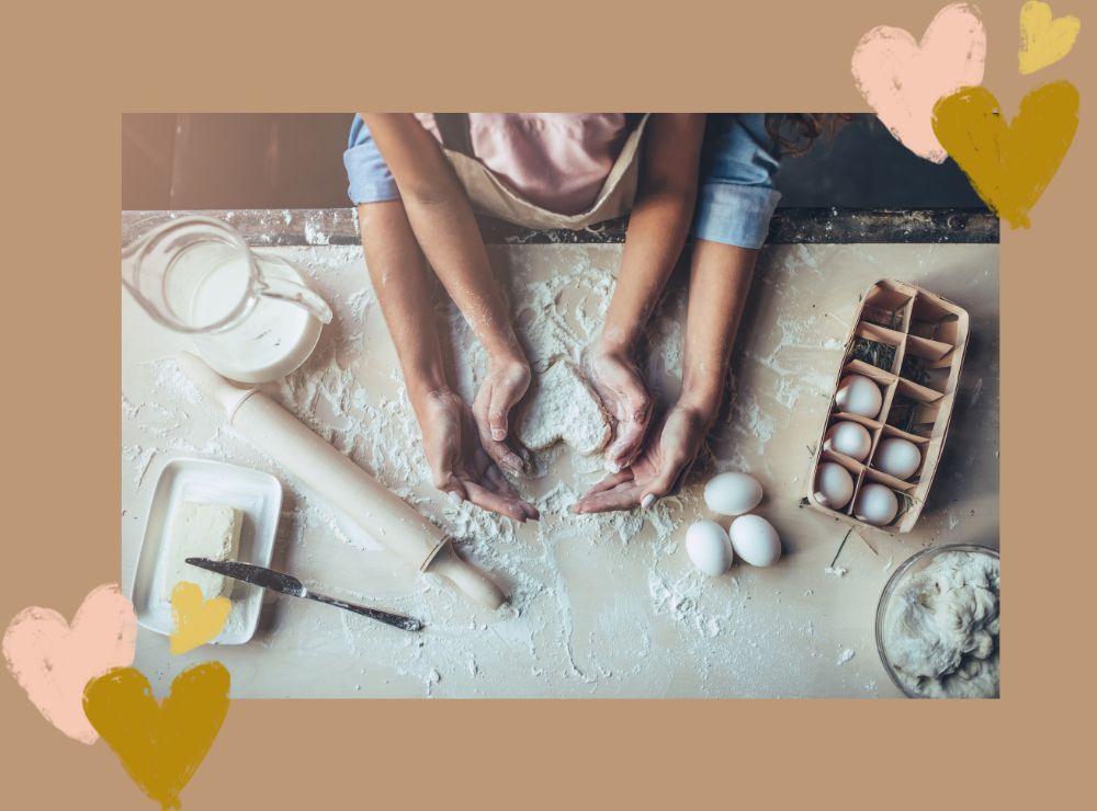 Two people holding a heart shaped cookie dough making a valentines day recipe together .