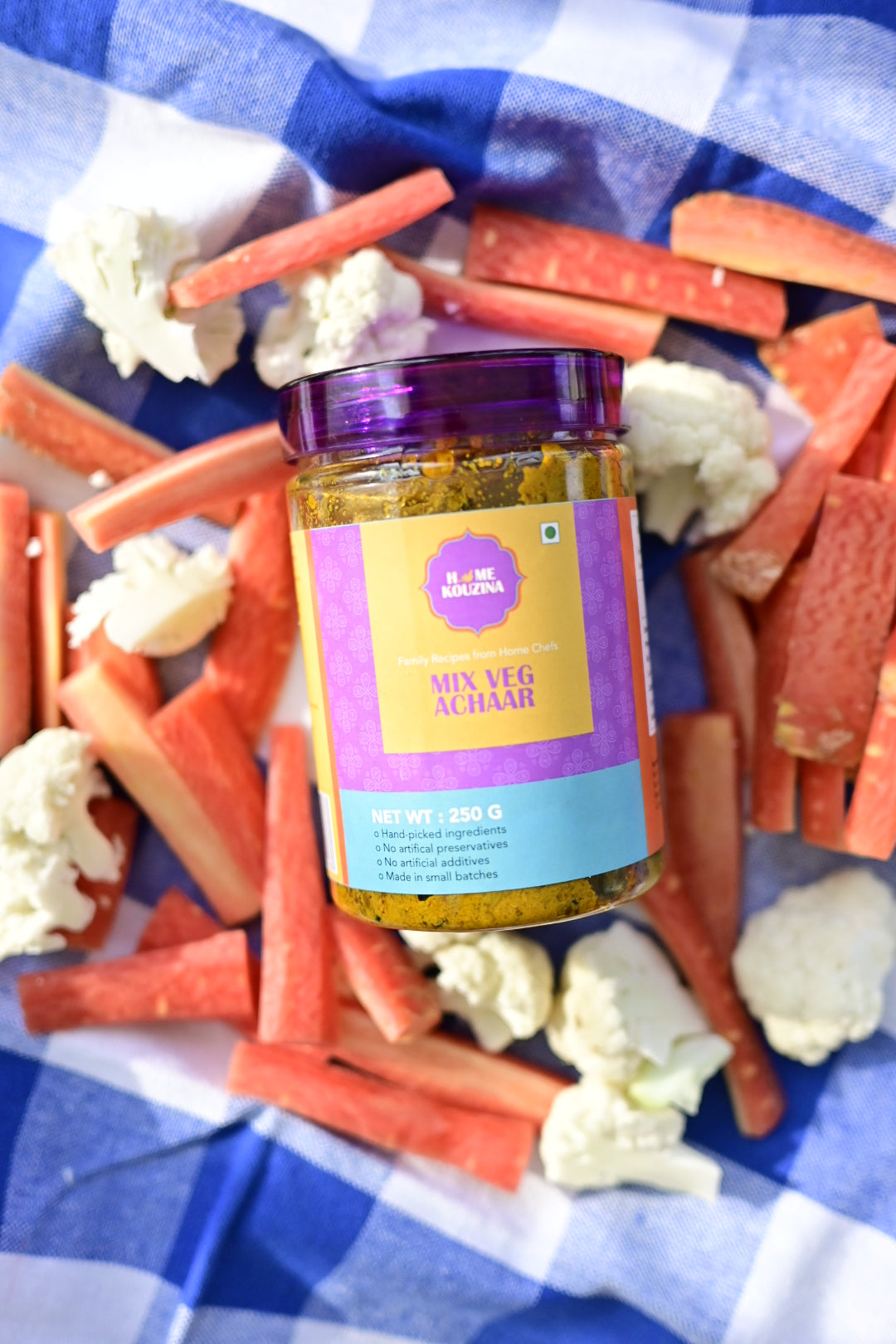 Mix Veg Achaar bottle with carrot sticks and cauliflower on a blue checkered cloth.