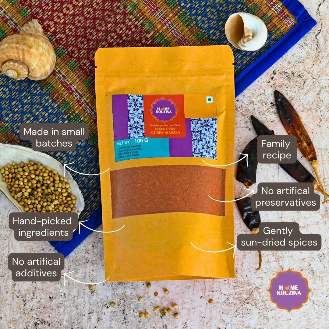 Top view of 100g Goan Fish Curry Masala pack surrounded by whole spices like coriander seeds, dried red chillies, and turmeric root for an authentic, rustic vibe