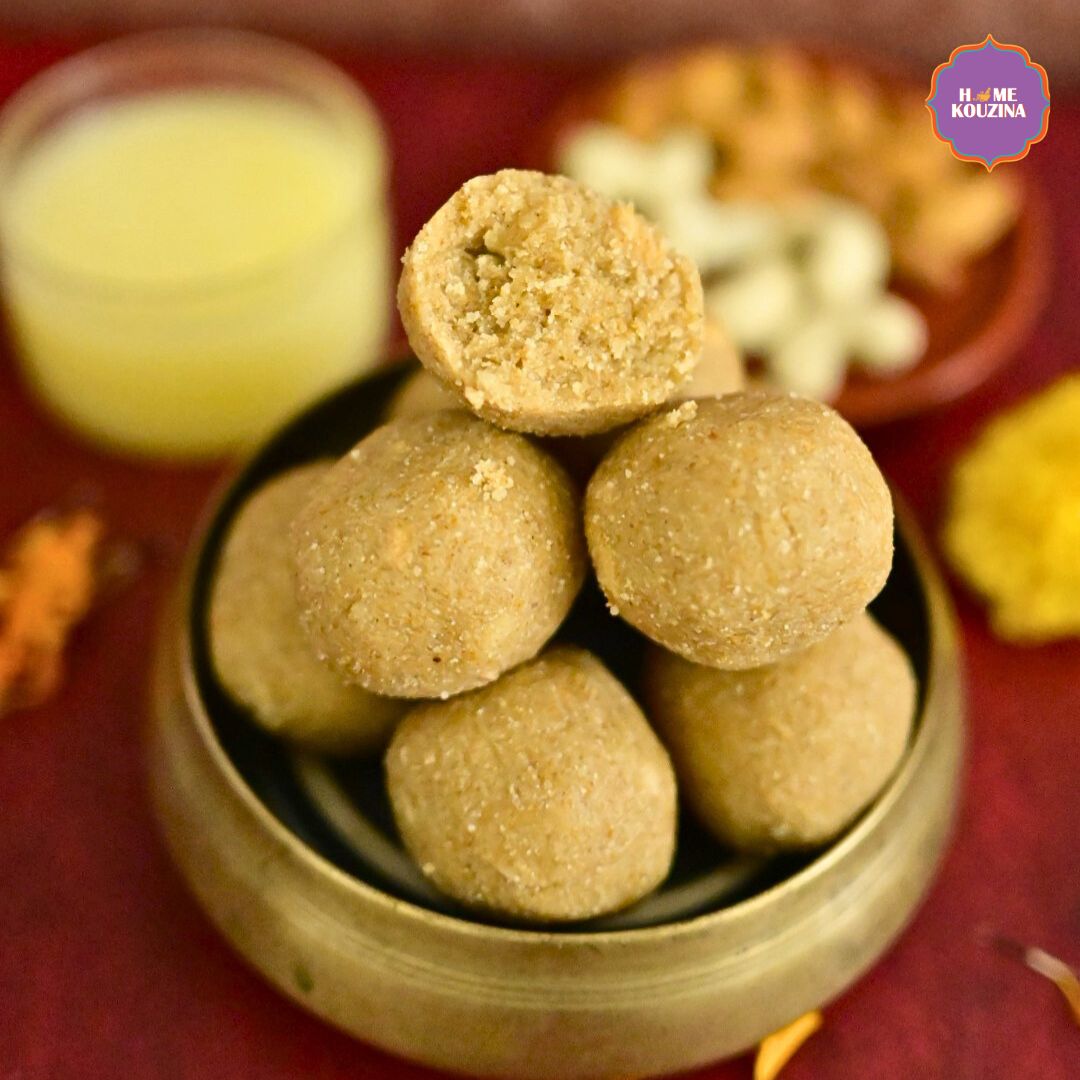 Close up of Home Kouzina's Atta Gond Laddoo stacked in a brass bowl with one laddoo broken open showing its texture, surrounded by ghee and dry fruits