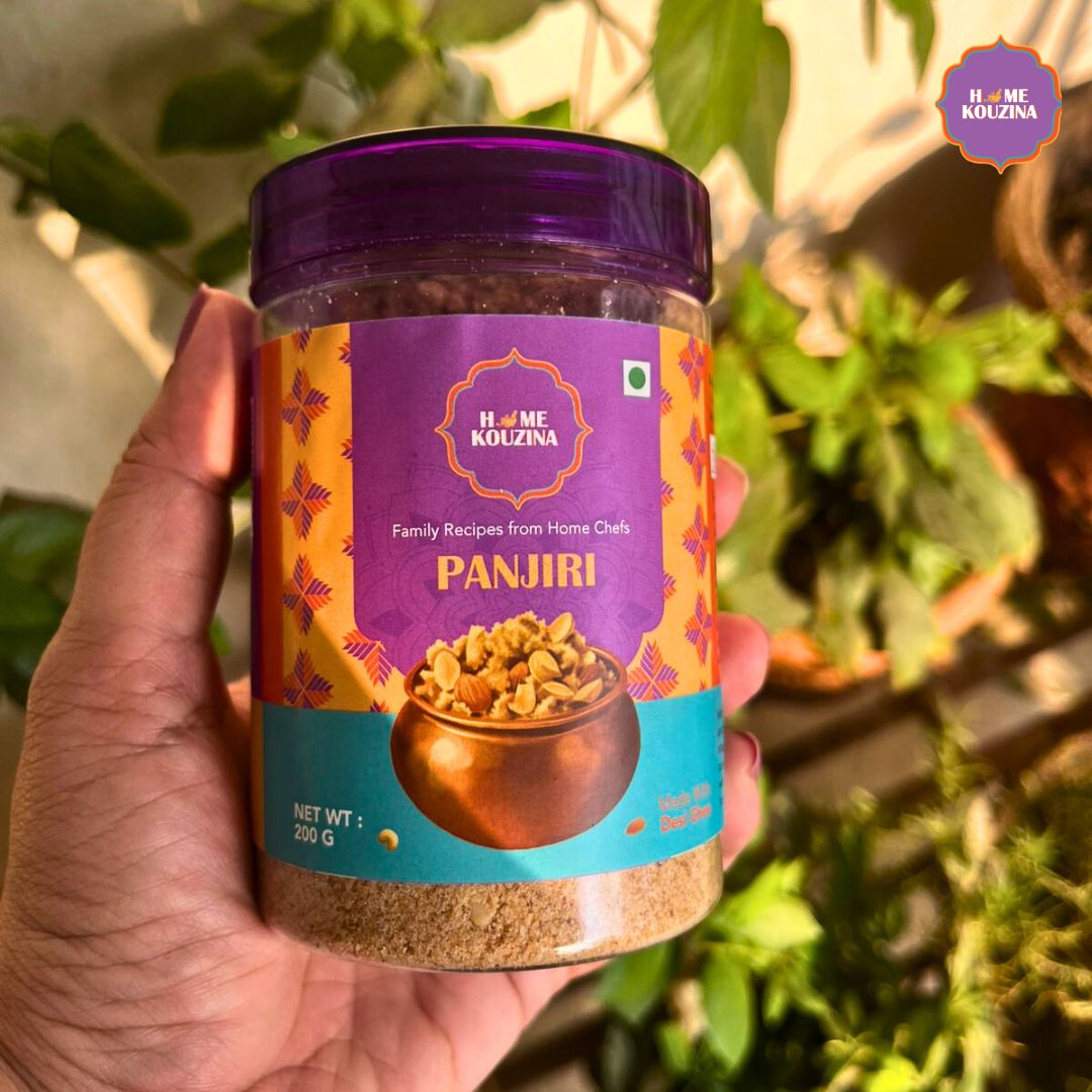 Hand holding a Home Kouzina Panjiri jar, wholesome Indian festive sweet made with desi ghee and dry fruits