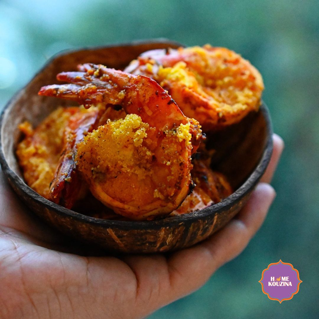 Hand holding a bowl of crispy golden prawns tossed in Goan Recheado Masala, rustic table background