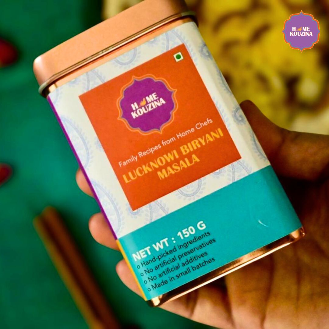 Top view of Home Kouzina Lucknowi Biryani Masala 150g tin held in hand against a clean background
