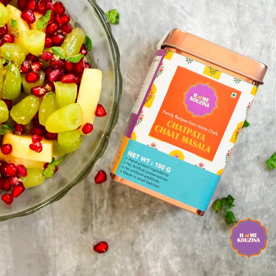 Top view of Home Kouzina Chatpata Chaat Masala 150g tin on table with colorful fruit chaat – small-batch, preservative-free masala for tangy and zesty chaat flavors