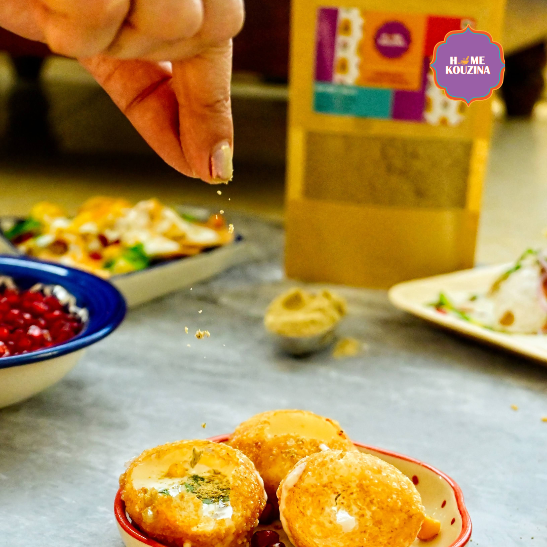 Close-up of hand sprinkling Home Kouzina Chatpata Chaat Masala on plate of chaat – aromatic, bold, and tangy Indian spice for street-style snacks