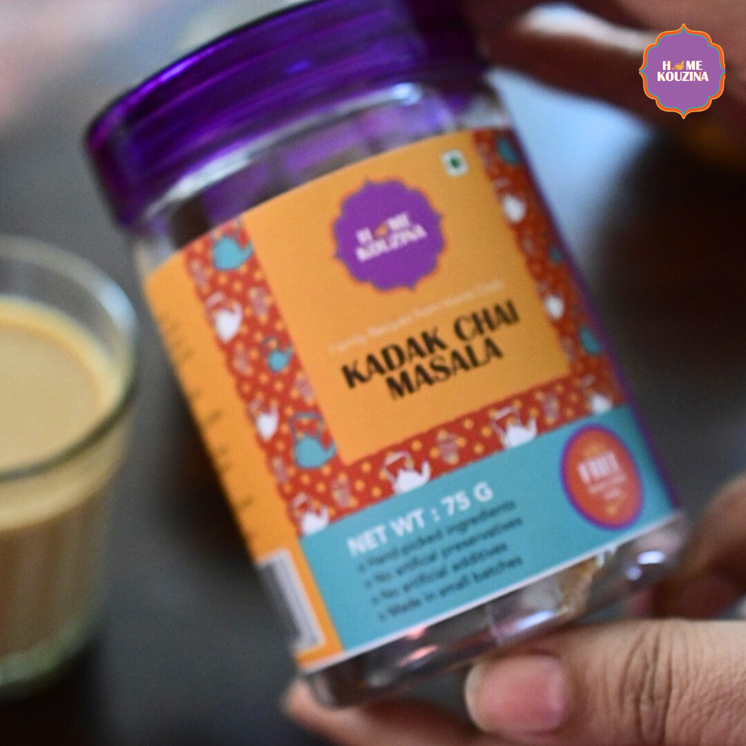 Jar of Kadak Chai Masala with a glass of chai in the background