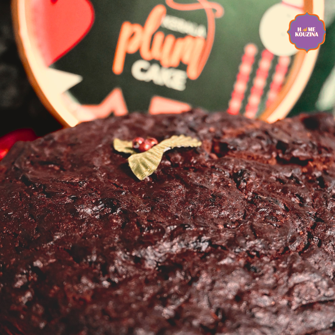 Close-up of a chocolate cake with a decorative leaf on top, with a blurred background featuring a cake box.