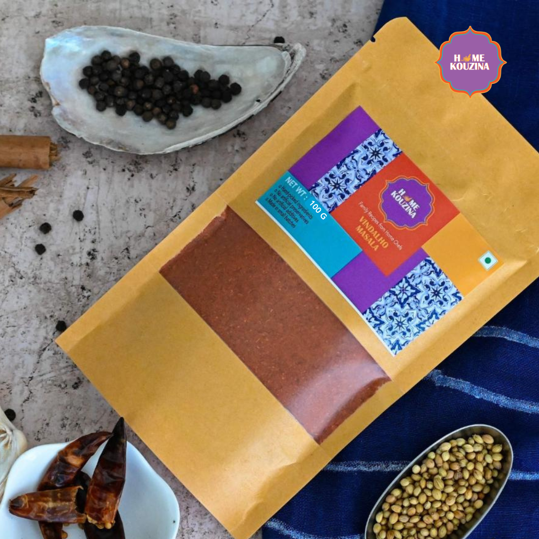 Top view of 100g Goan Vindalho Masala pouch on a table with whole spices scattered around for a warm, homely feel