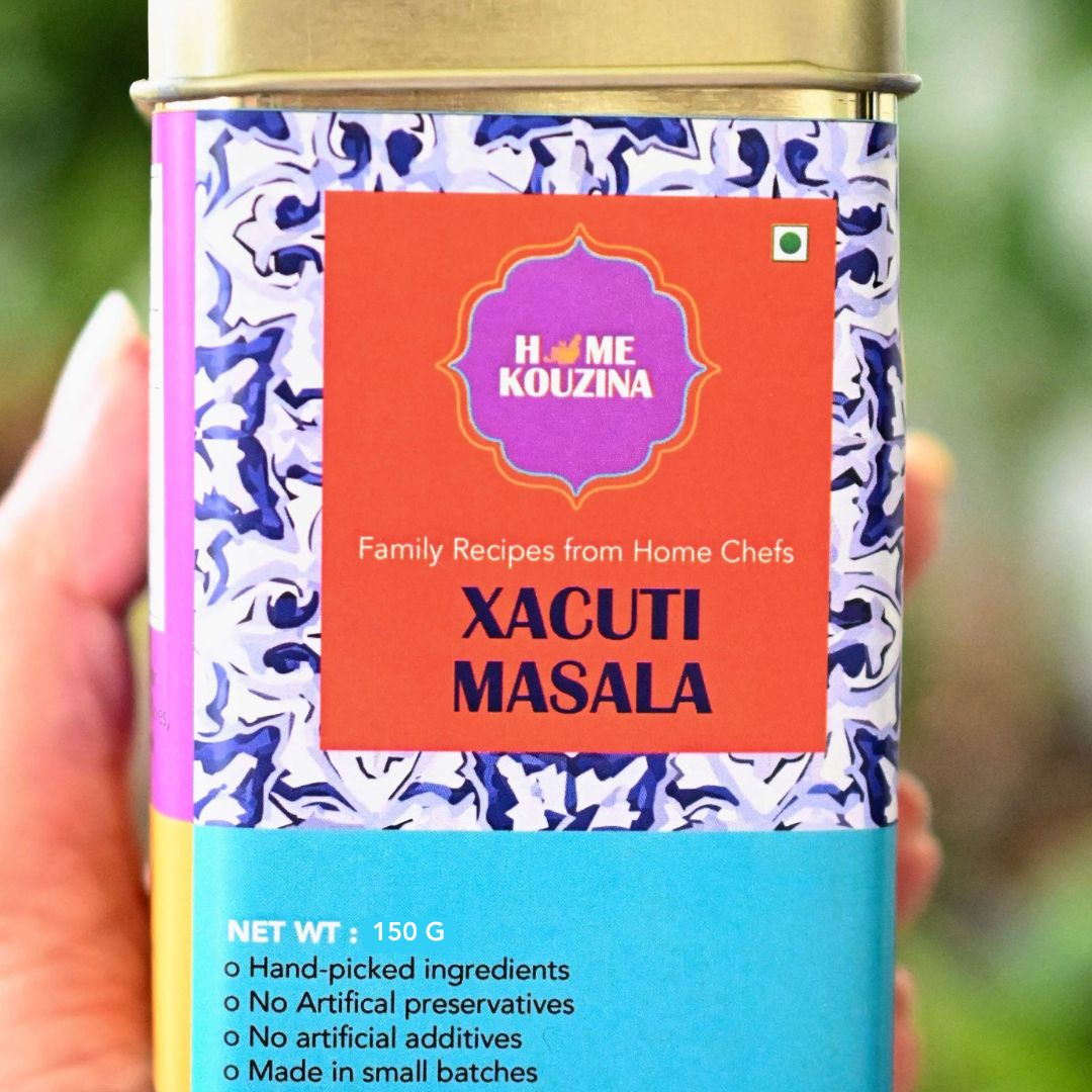 Front view holding 150g Goan Xacuti Masala tin in hand, white background, highlighting authentic small-batch, preservative-free blend