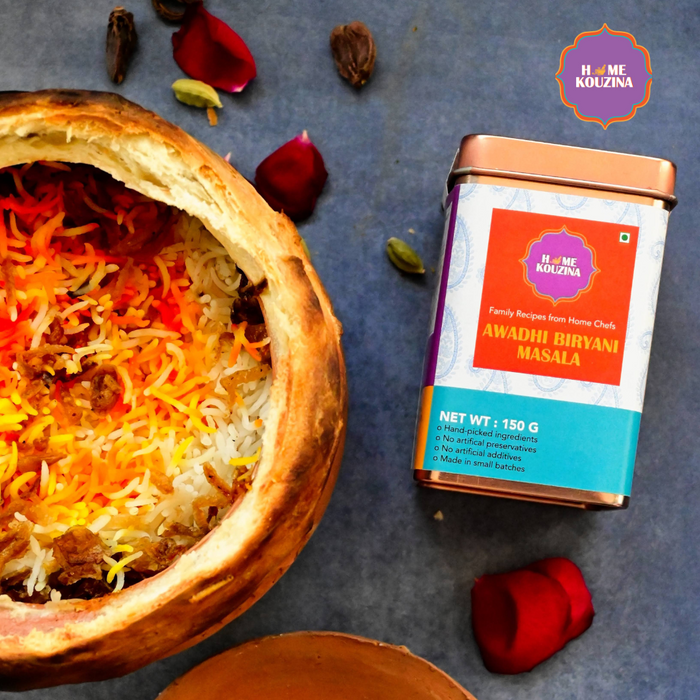 Traditional homemade Lucknowi Awadhi Biryani freshly made and placed in an earthen bowl with garnish and the Home Kouzina Awadhi Biryani Masala tin product next to it