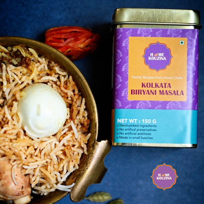 Traditional homemade Kolkata Biryani freshly made and placed in an earthen bowl with garnish and the Home Kouzina Kolkata Biryani Masala tin product next to it